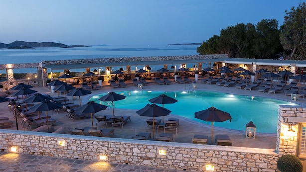 A pool area with lounge chairs and umbrellas, surrounded by stone walls and overlooking the sea. - Saint Andrea Sea Side Resort - Adults Only (Paros)