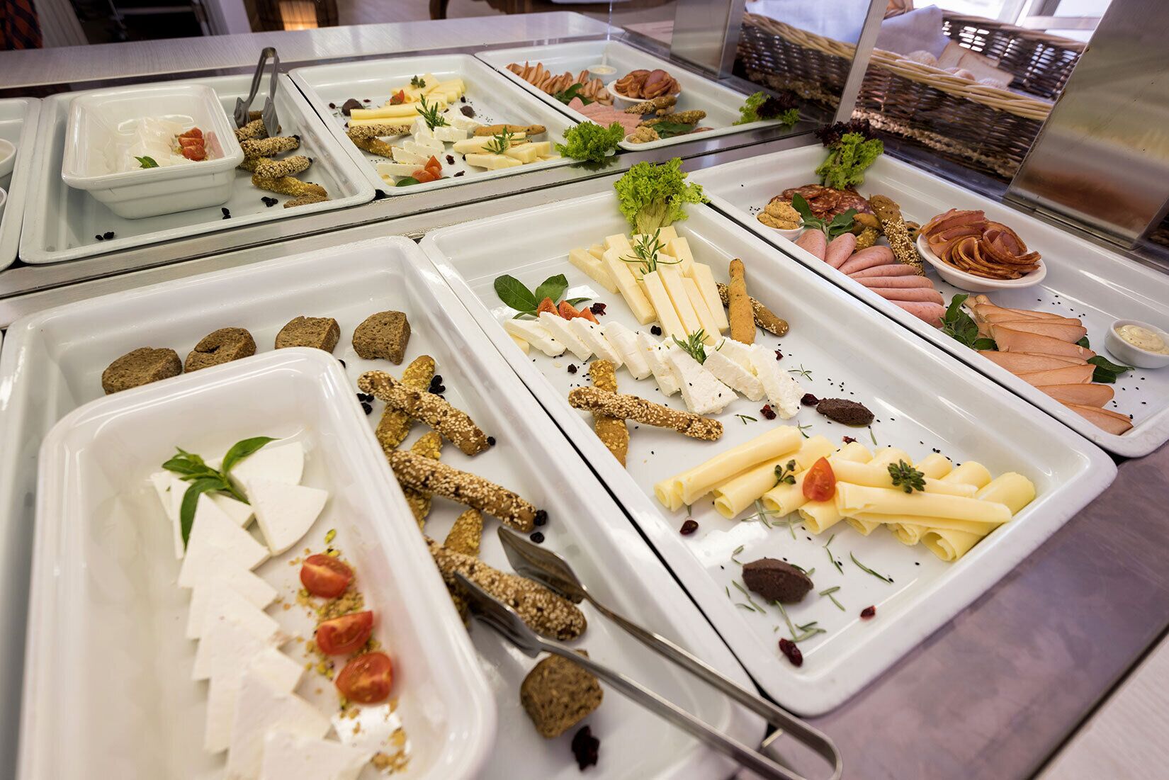 A buffet with various food items including cheeses, meats, and vegetables.