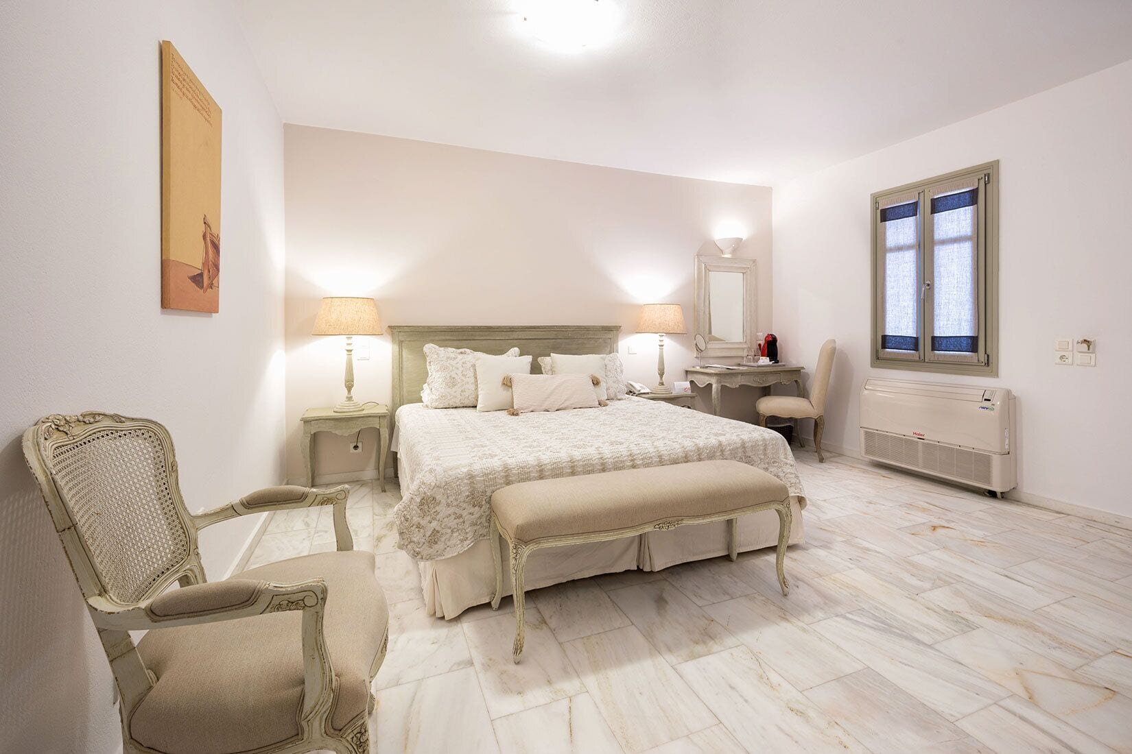 A bedroom with a bed, two bedside tables, a chair, a desk, a mirror, and a window.