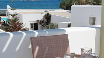 Una terraza con vistas al mar, edificios blancos y una mesa con una jarrón y una taza.