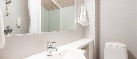 A bathroom with a white sink, a mirror, a shower, and a toilet.