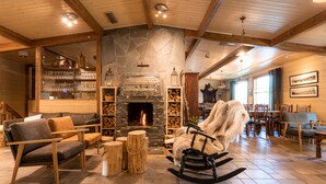 Ein gemütliches Interieur mit Kamin aus Stein, Holzmöbeln und einer Essecke.