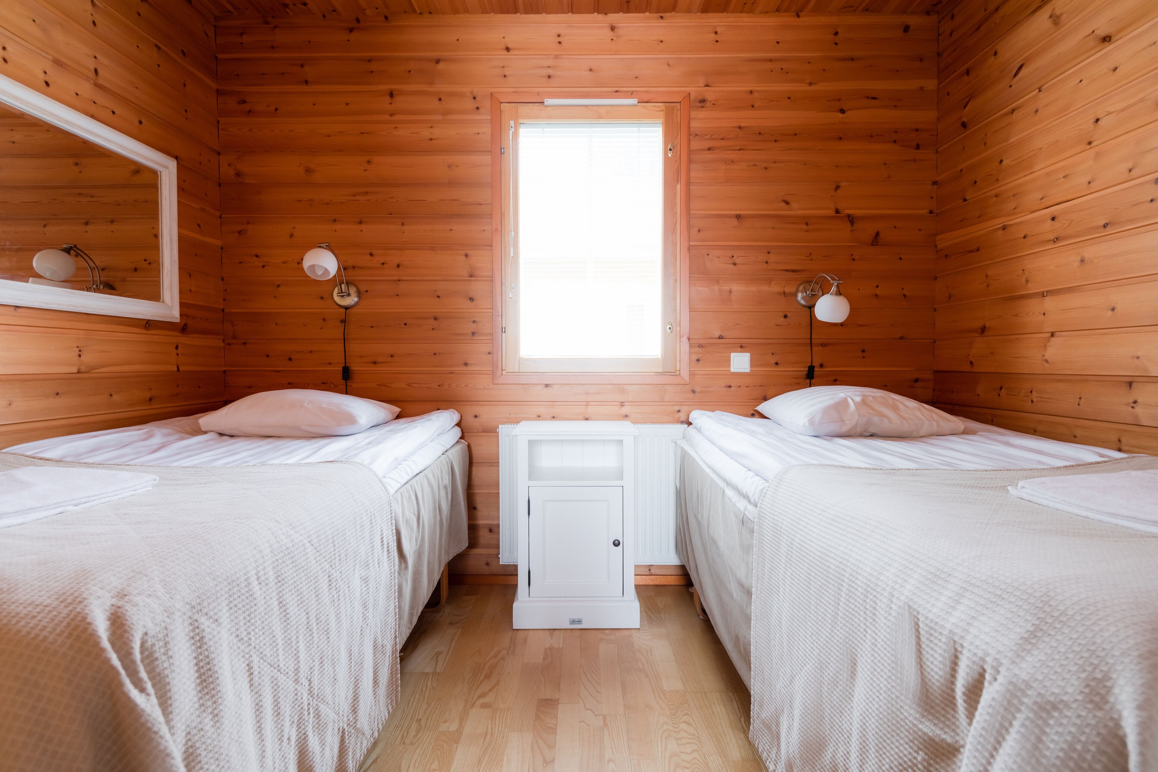 Una habitación con dos camas, una ventana y una mesita de noche con lámparas.
