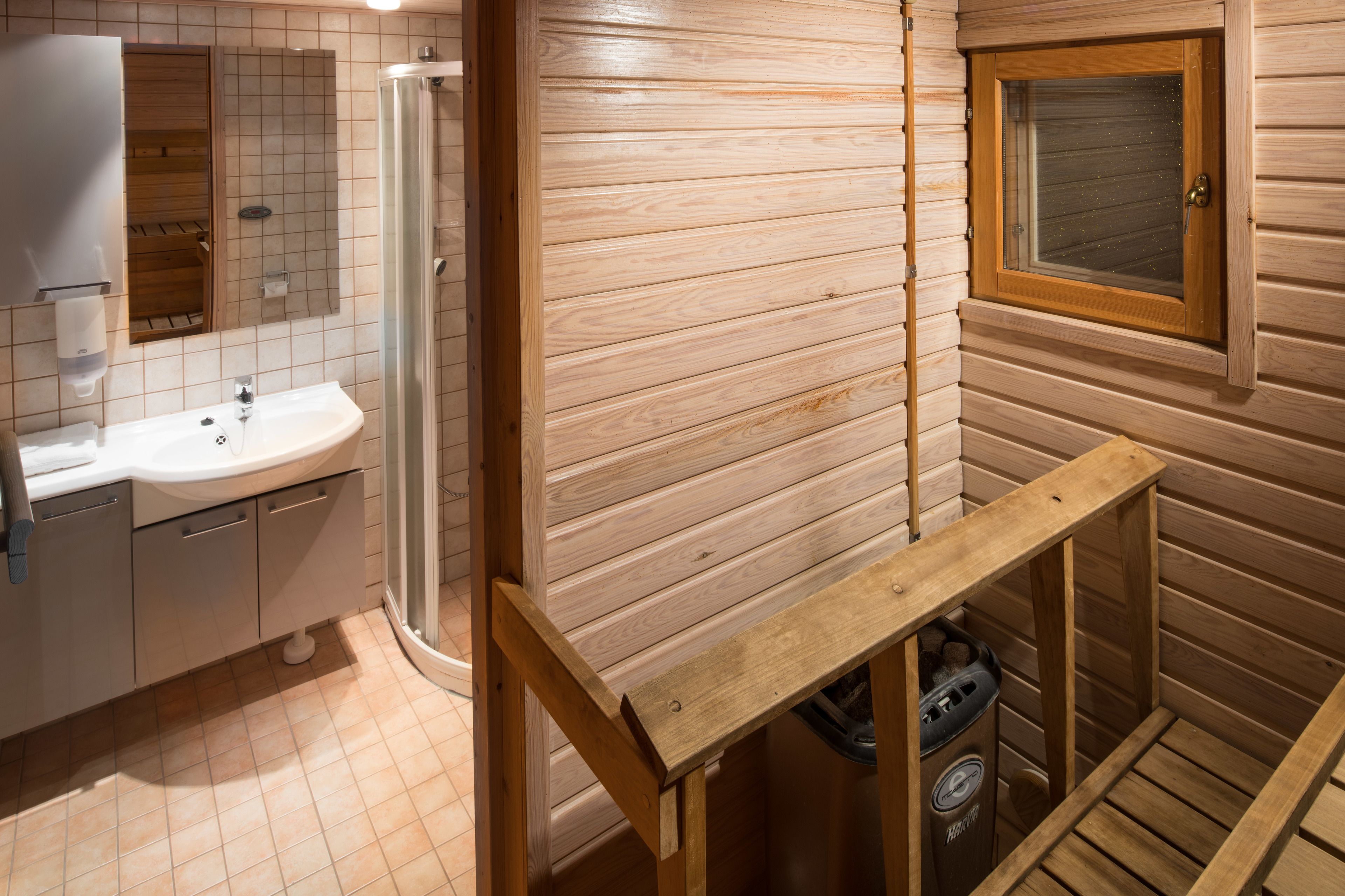 Baño de cabaña de madera con lavabo, espejo y ventana.