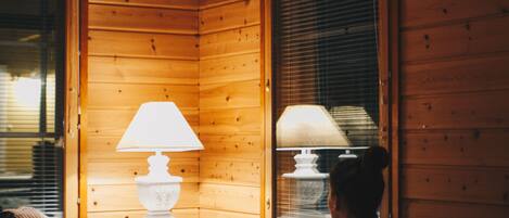 A cozy room with wooden walls, a sofa, a table with a lamp, and a laptop.