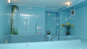 Een badkamer met blauwe tegels, een toilet, een wastafel en een douche.