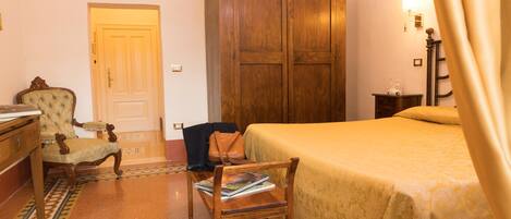 Ein Hotelzimmer mit Bett, Holzschrank, Stuhl, Schreibtisch und Lampe.