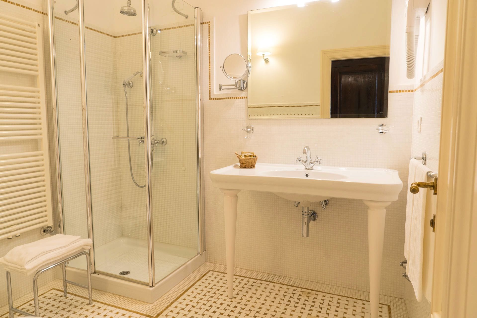 Casa de banho com chuveiro envidraçado, lavatório com espelho e porta-toalhas.