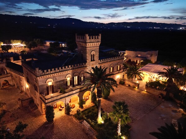 Un edificio histórico con un patio, palmeras y una torre.