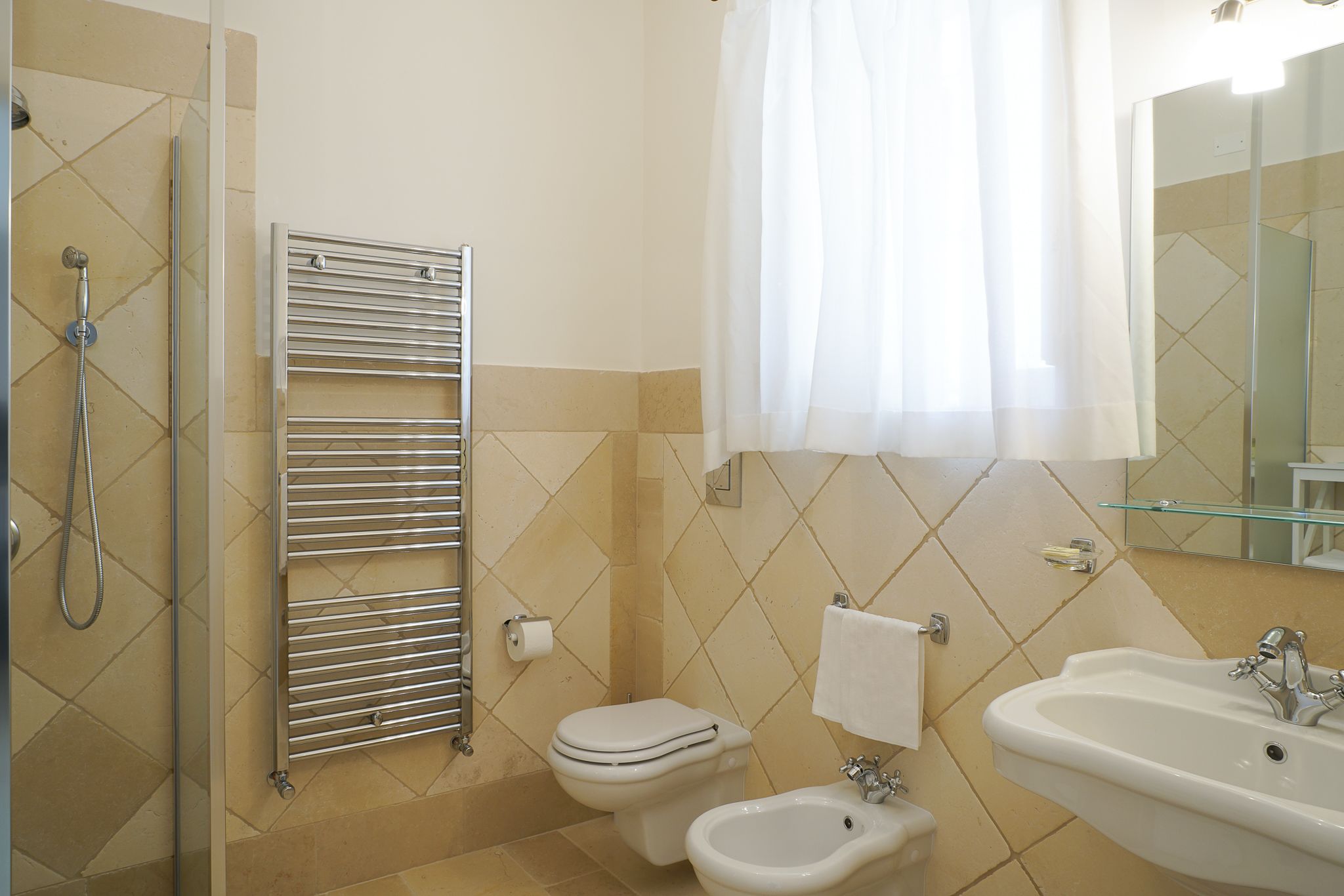 A bathroom with a shower, toilet, bidet, and sink.