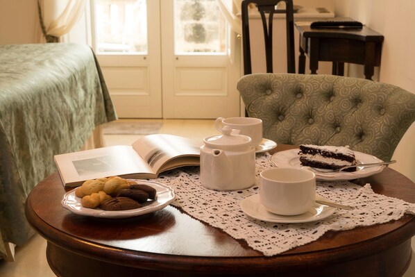 A cozy dining area with a table set for tea, a book, cookies, and a slice of cake. - Masseria Salamina (Fasano)