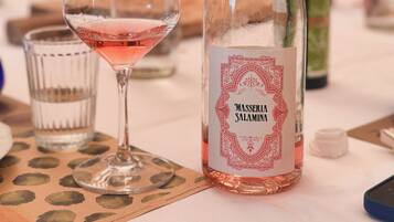 A bottle of "Masseria Salamina" wine and a glass of pink wine on a table with a placemat.
