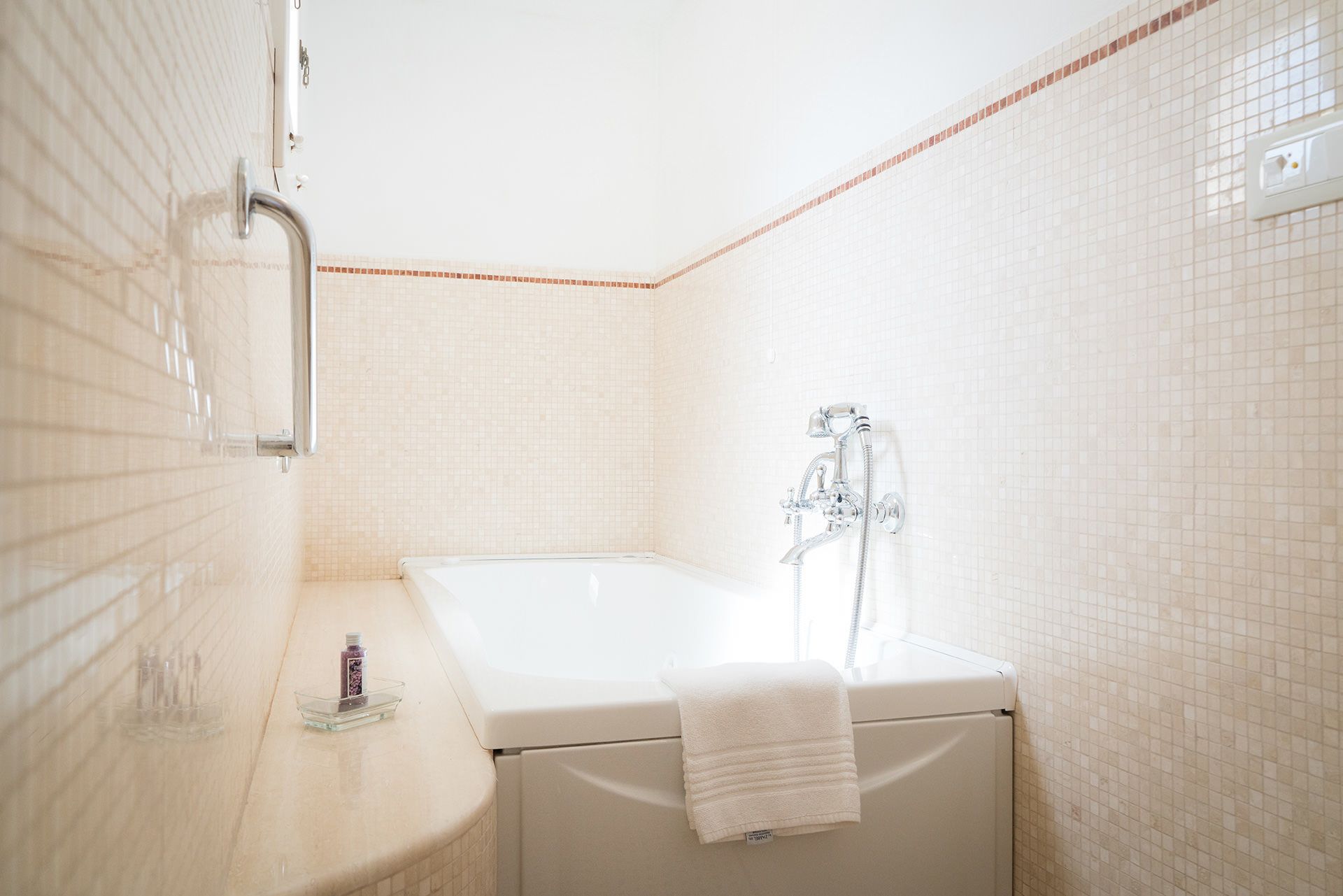 A bathroom with a bathtub, a showerhead, and a towel rack.