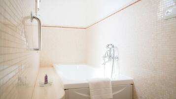 A bathroom with a bathtub, a showerhead, and a towel rack.