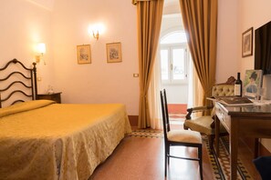 A hotel room with a bed, a desk with a chair, a lamp, and two framed pictures on the wall. - Masseria Salamina (Fasano)