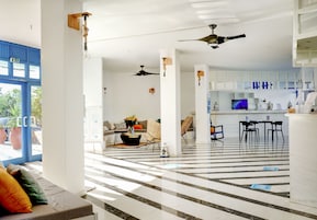 Un vestíbulo espacioso con suelo a cuadros, una zona de estar con sofá y sillones, y un área de cocina con mostrador y sillas.