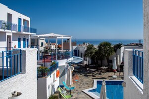 Un área de piscina en la azotea con vistas al mar, mobiliario exterior y un porche cubierto.