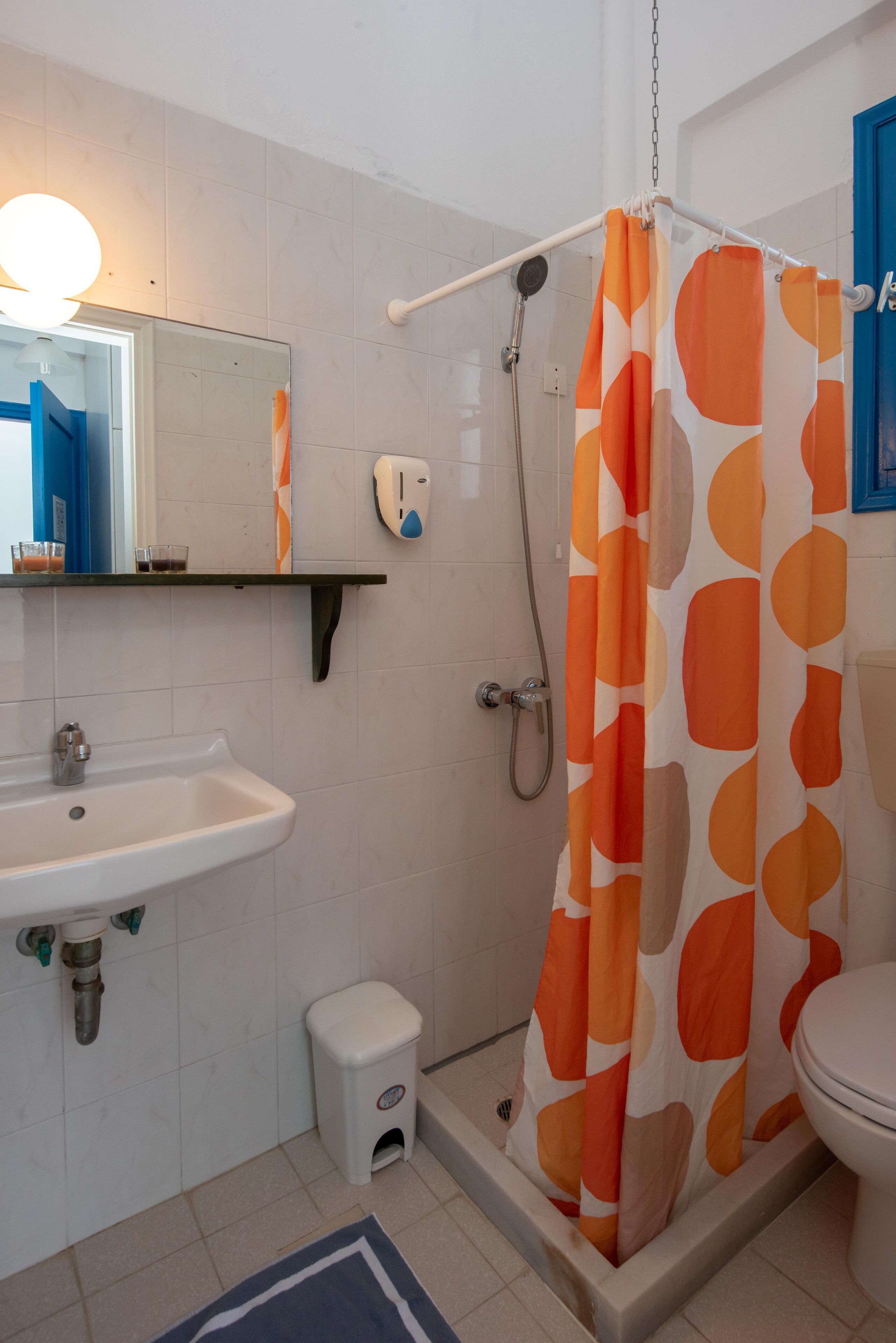 A bathroom with a sink, toilet, shower, and a mirror.