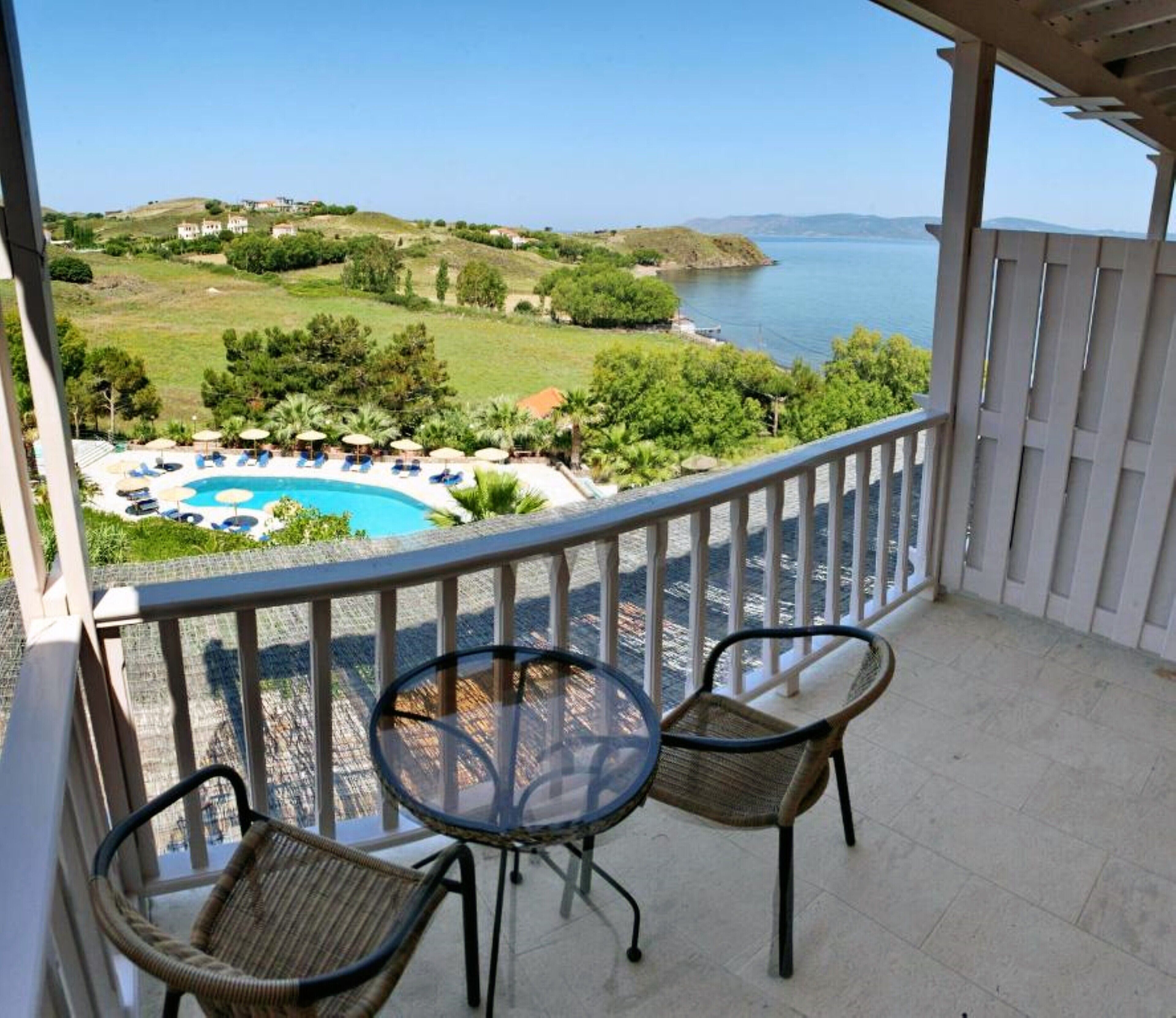A balcony with a view of a pool and the sea.