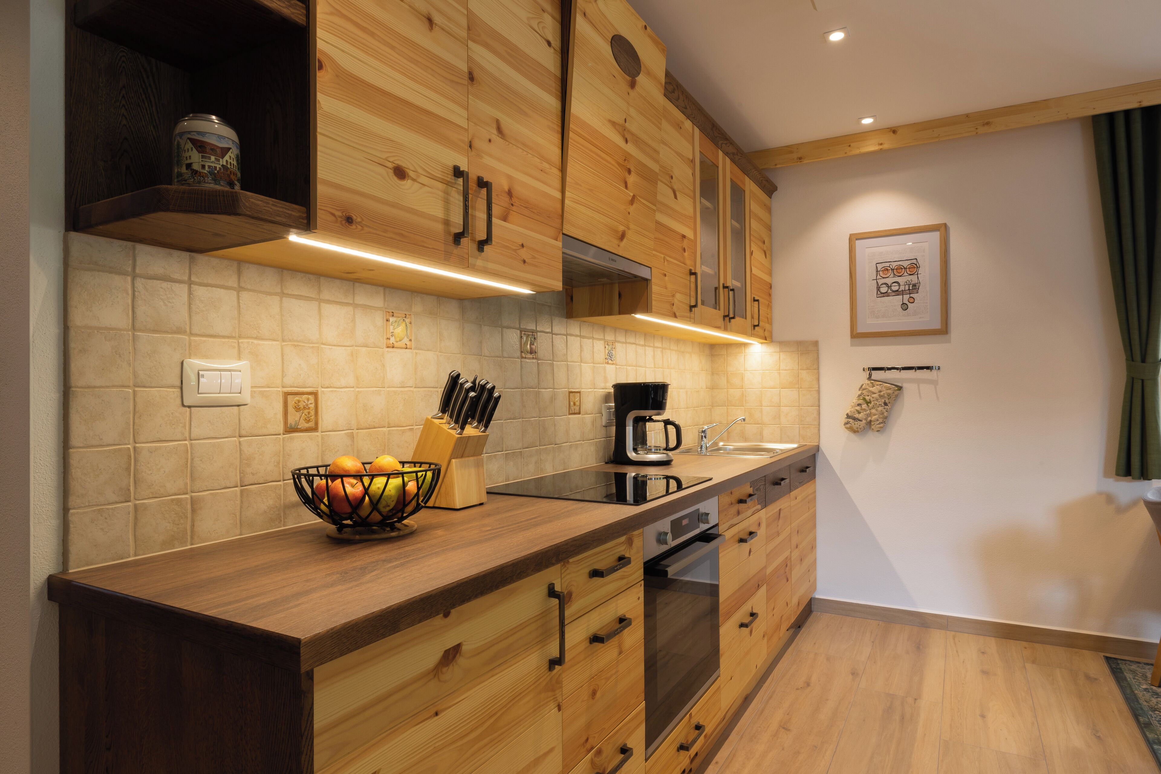 A kitchen with wooden cabinets, a countertop with a fruit bowl, a coffee maker, and a knife block.