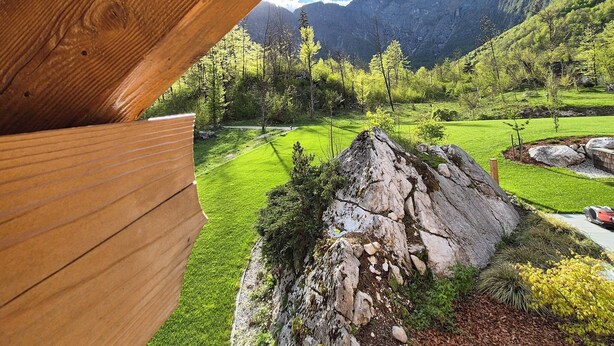 A wooden structure with a view of a green landscape, including a grassy area, trees, and mountains. - PRIVILLAGE STARE - B&B, Villa and Chalet Resort (Bohinj)