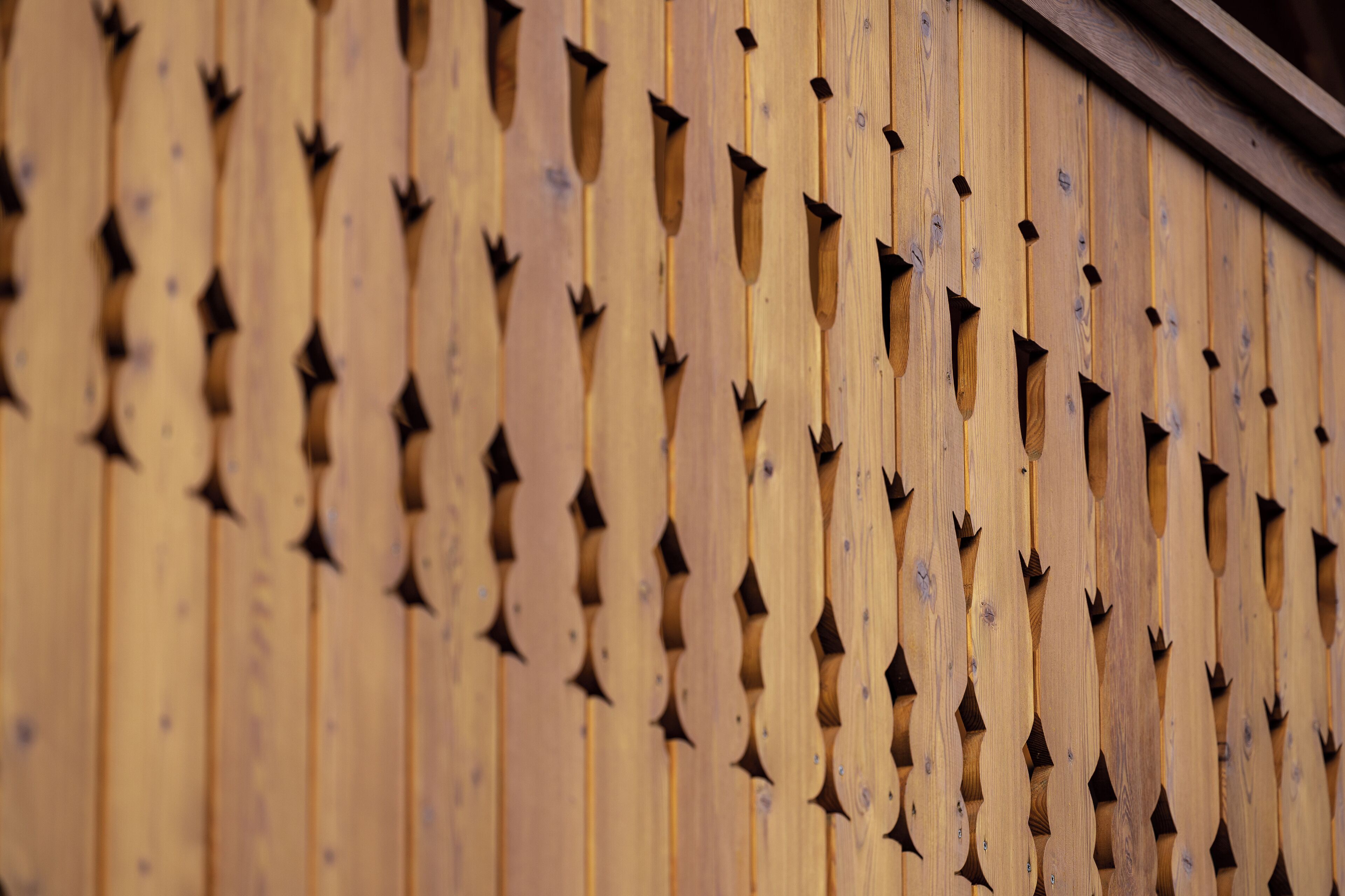 Un mur en bois orné d’ouvertures régulièrement espacées, ayant la forme d’étoiles.