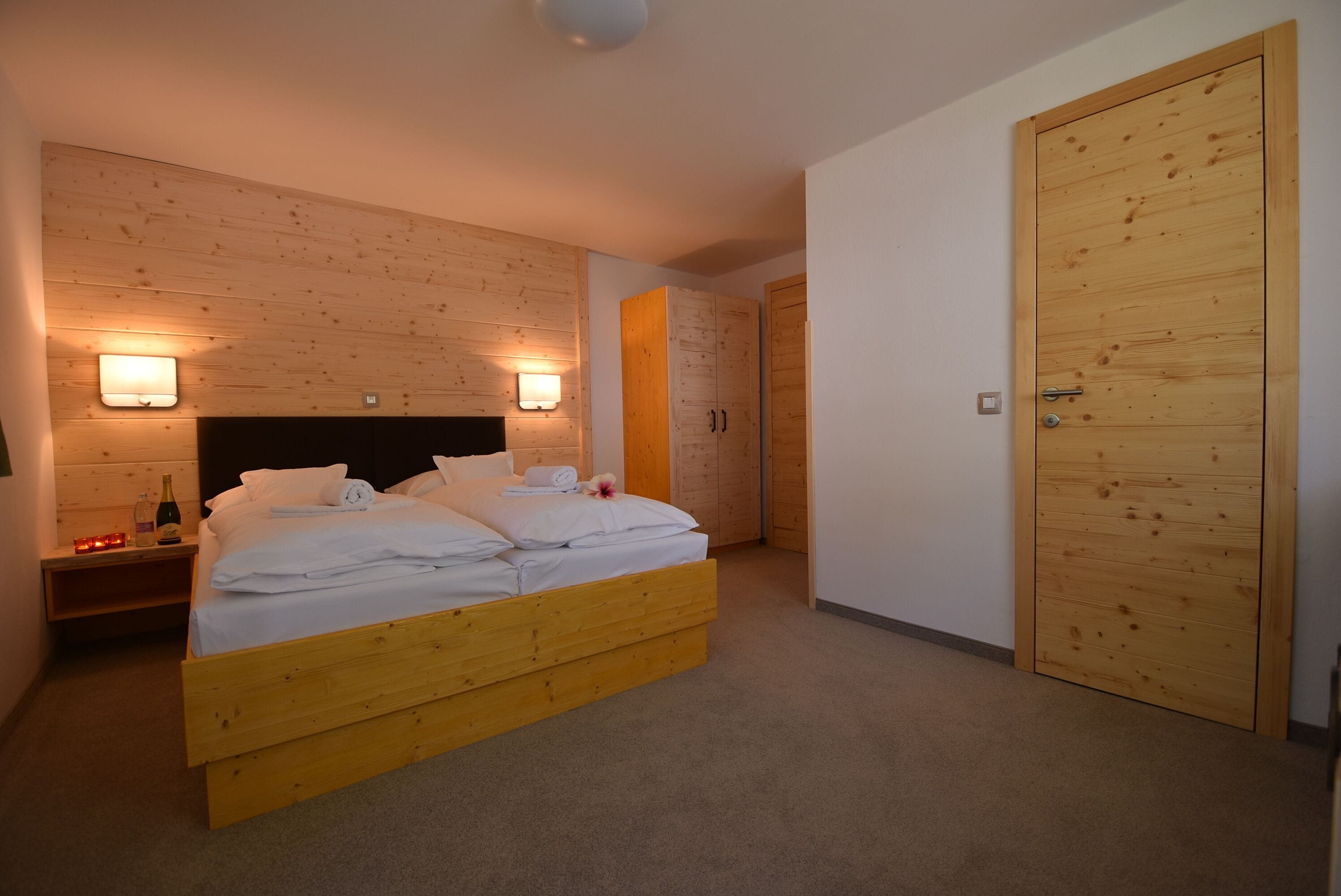 Un dormitorio con cama de madera, dos mesitas de noche, un aparador y un armario de madera.