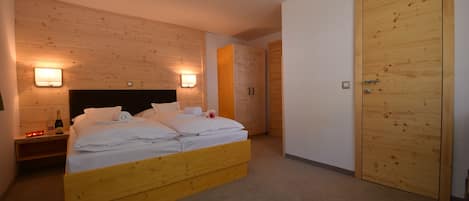 Un dormitorio con cama de madera, dos mesitas de noche, un aparador y un armario de madera.