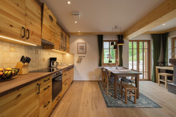 Una cocina moderna con armarios de madera, horno integrado y un comedor con mesa y sillas.