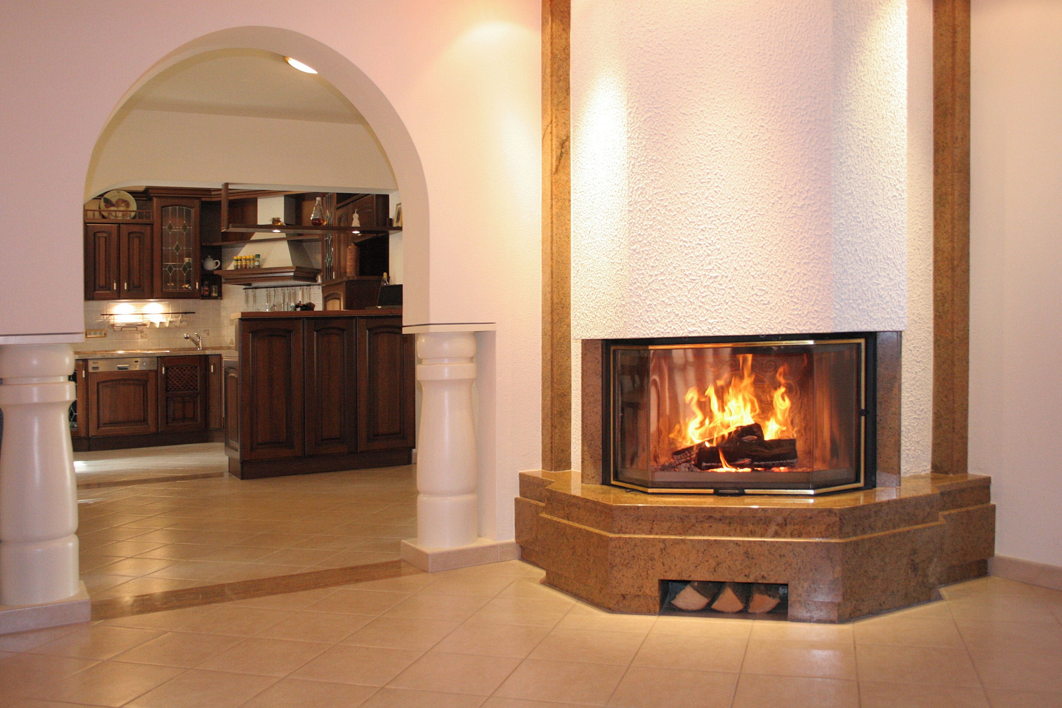 A modern kitchen with a fireplace, wooden cabinets, and a tiled floor.