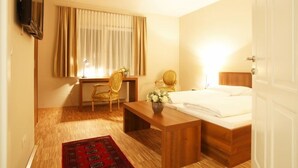 Ein Hotelzimmer mit Bett, Schreibtisch, Stuhl und Fernseher.