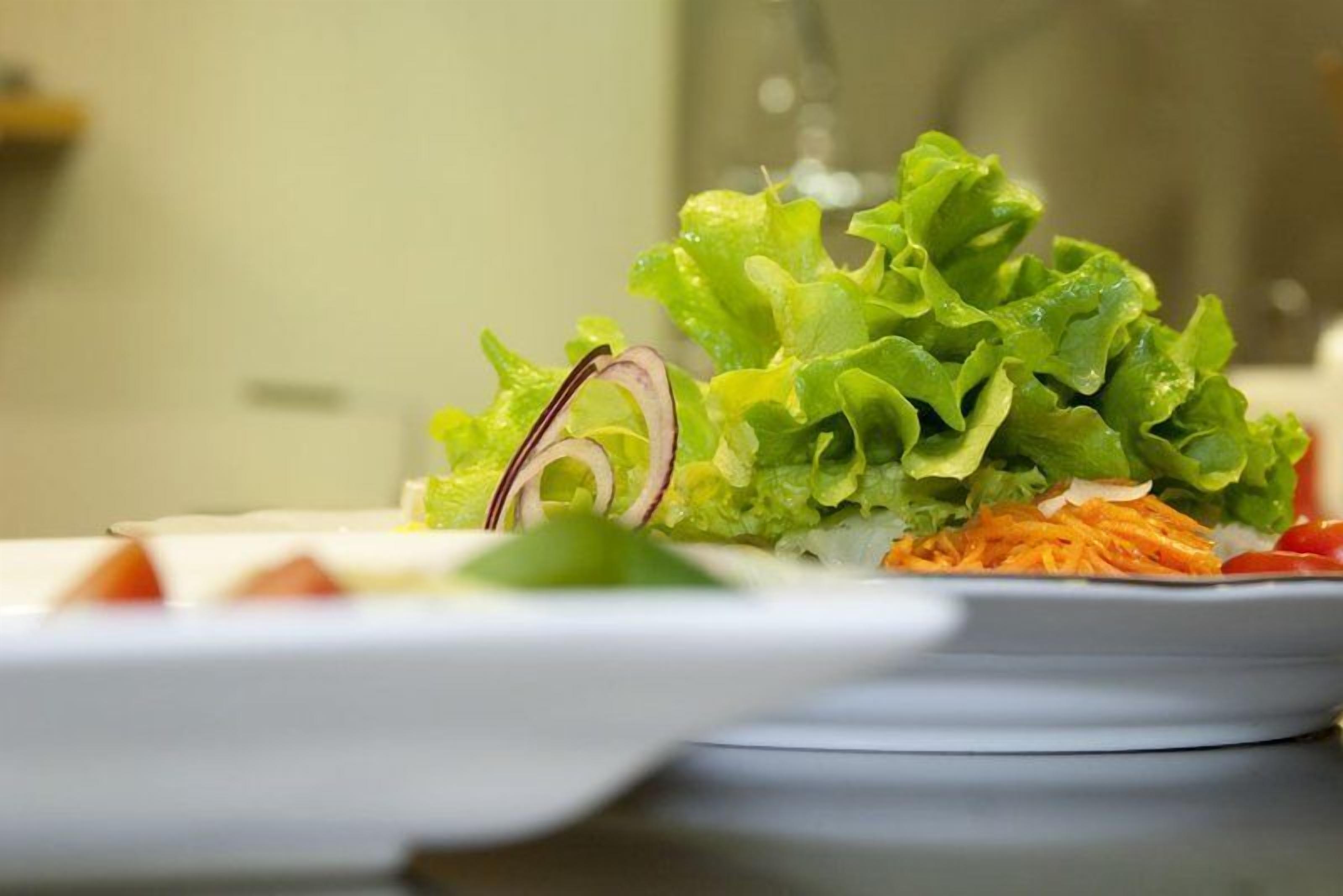 A plate of fresh salad with lettuce, carrots, and onions.