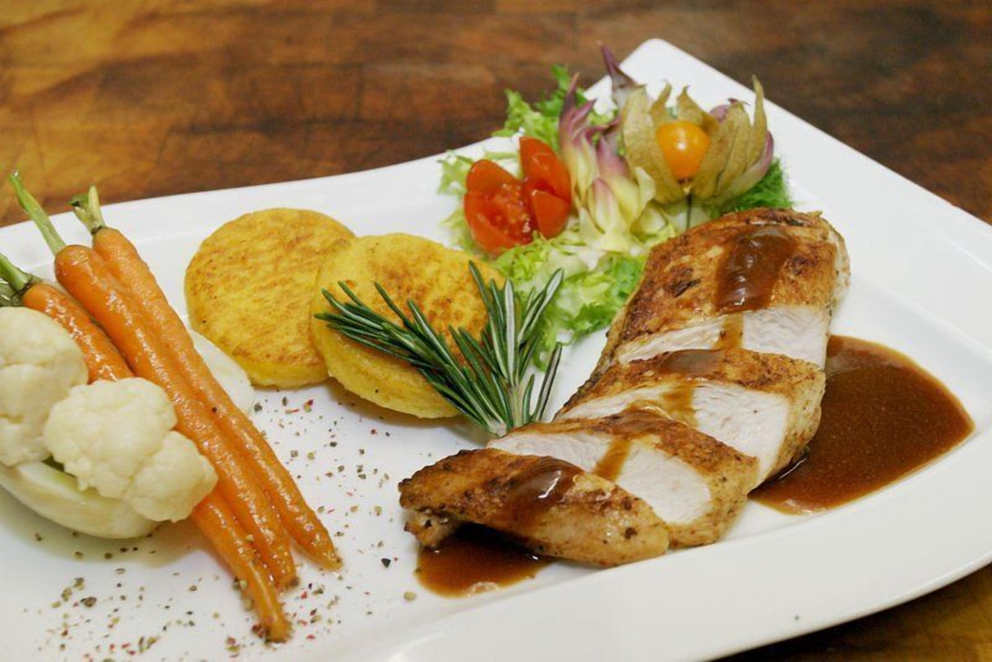A plate of food with a piece of grilled chicken, carrots, cauliflower, and a side salad.