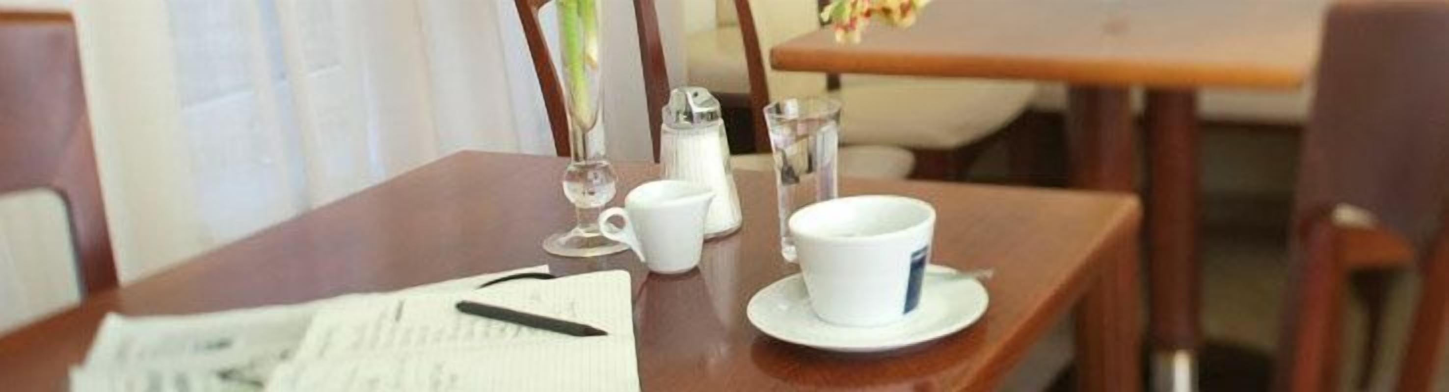 Una mesa de madera con una taza, platillo y un vaso de agua.