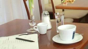 Una mesa de madera con una taza, platillo y un vaso de agua.