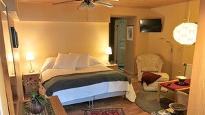 A cozy bedroom with a bed, bedside lamps, a chair, a small table with a bowl, and a TV on the wall. - Mattisgården Bed & Breakfast (Klippan)