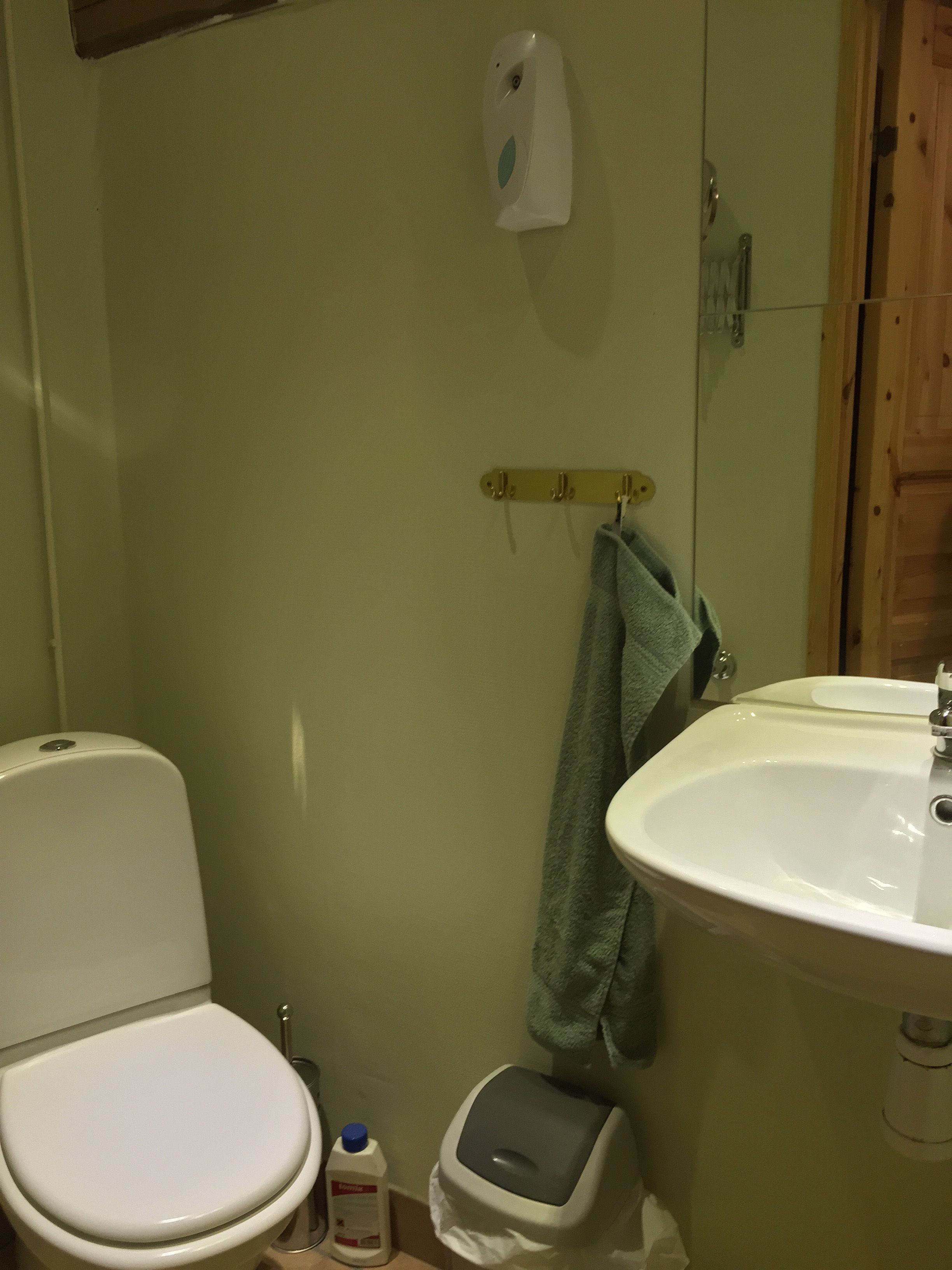 A bathroom with a toilet, sink, and hand dryer.