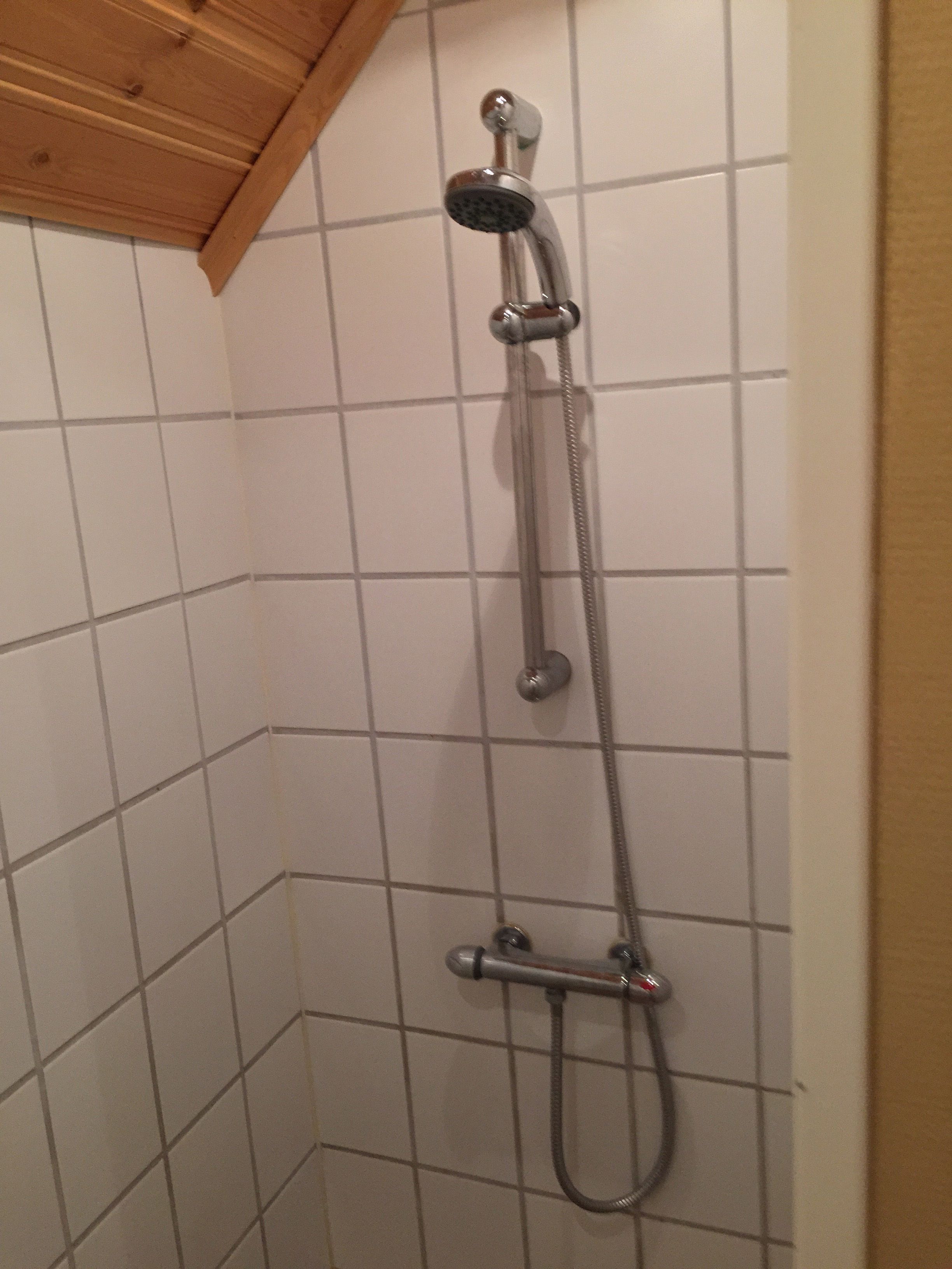 A shower with a handheld showerhead and a handheld hose.