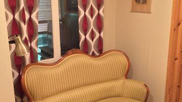 Una habitación con un sofá a rayas, una cortina estampada, una lámpara y un cuadro en la pared.