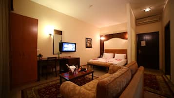 A hotel room with a bed, a sofa, a desk, a television, and a large mirror.