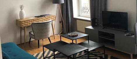Una sala de estar moderna con un sofá, una mesa de centro, un televisor, un escritorio y una lámpara.