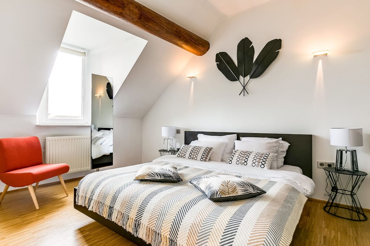 Ein modernes Schlafzimmer mit einem großen Bett, einem roten Sessel und einem Oberlicht.