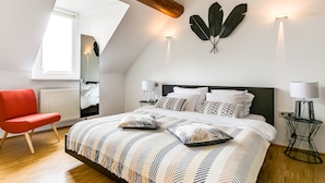Un dormitorio moderno con una cama grande, una silla roja y un tragaluz.