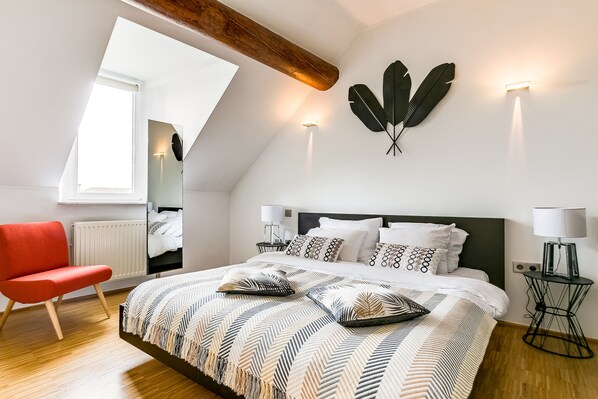 Un dormitorio moderno con una cama grande, una silla roja y un tragaluz.