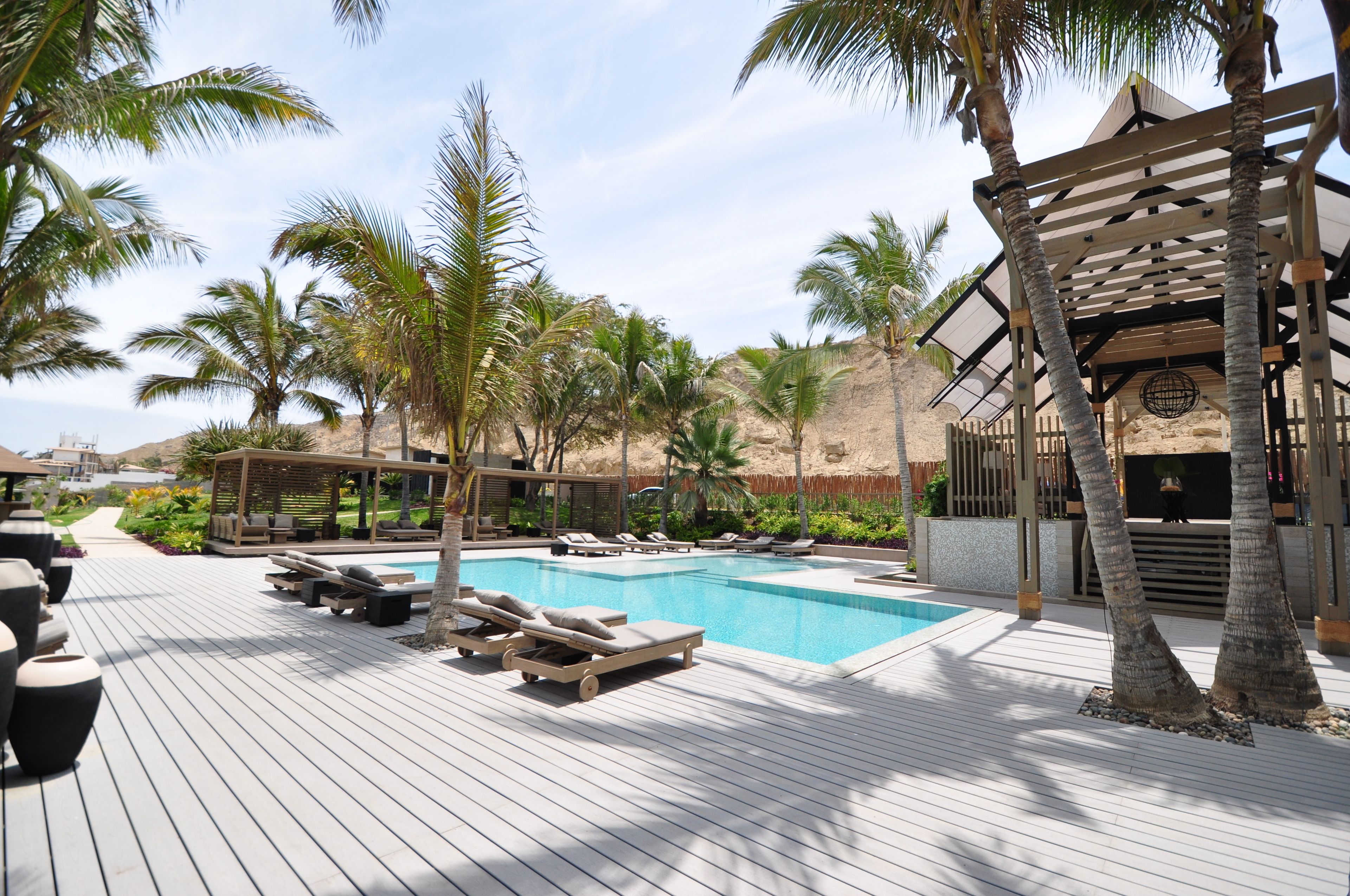 Un área de piscina con sillones de descanso y una terraza de madera.