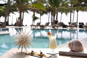 A poolside table with a cocktail, a decorative shell, and a book titled "New New York Interiors".