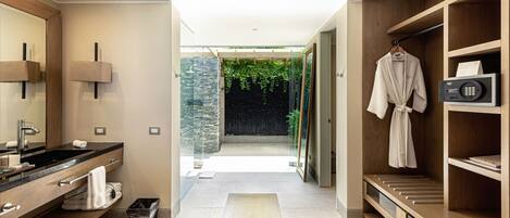 A modern bathroom with a large mirror, dual sinks, a robe rack, and a built-in heater.