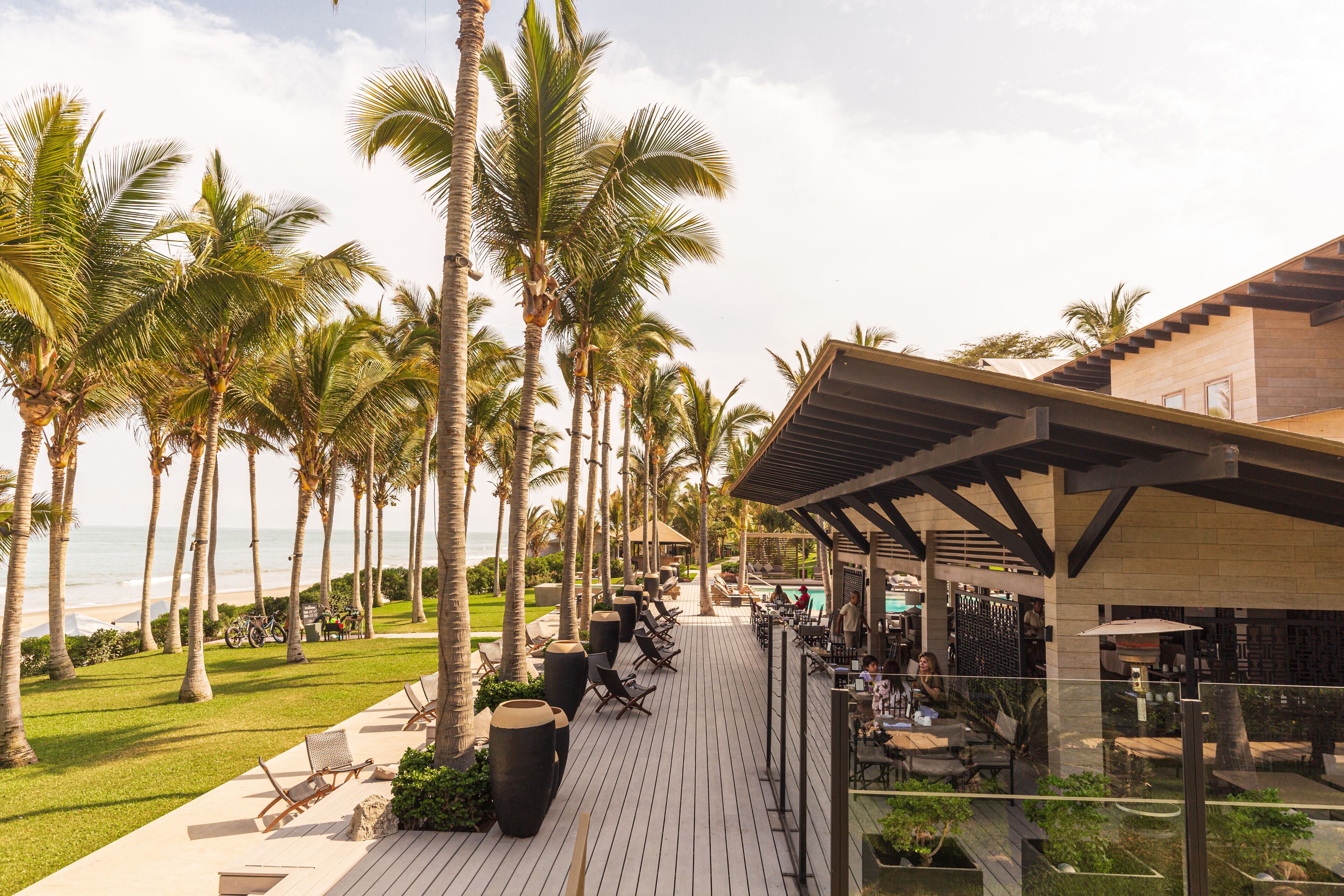 A resort with a wooden deck, palm trees, and a pool area.