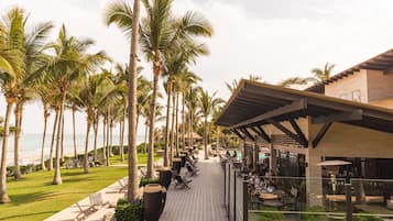 A resort with a wooden deck, palm trees, and a pool area.
