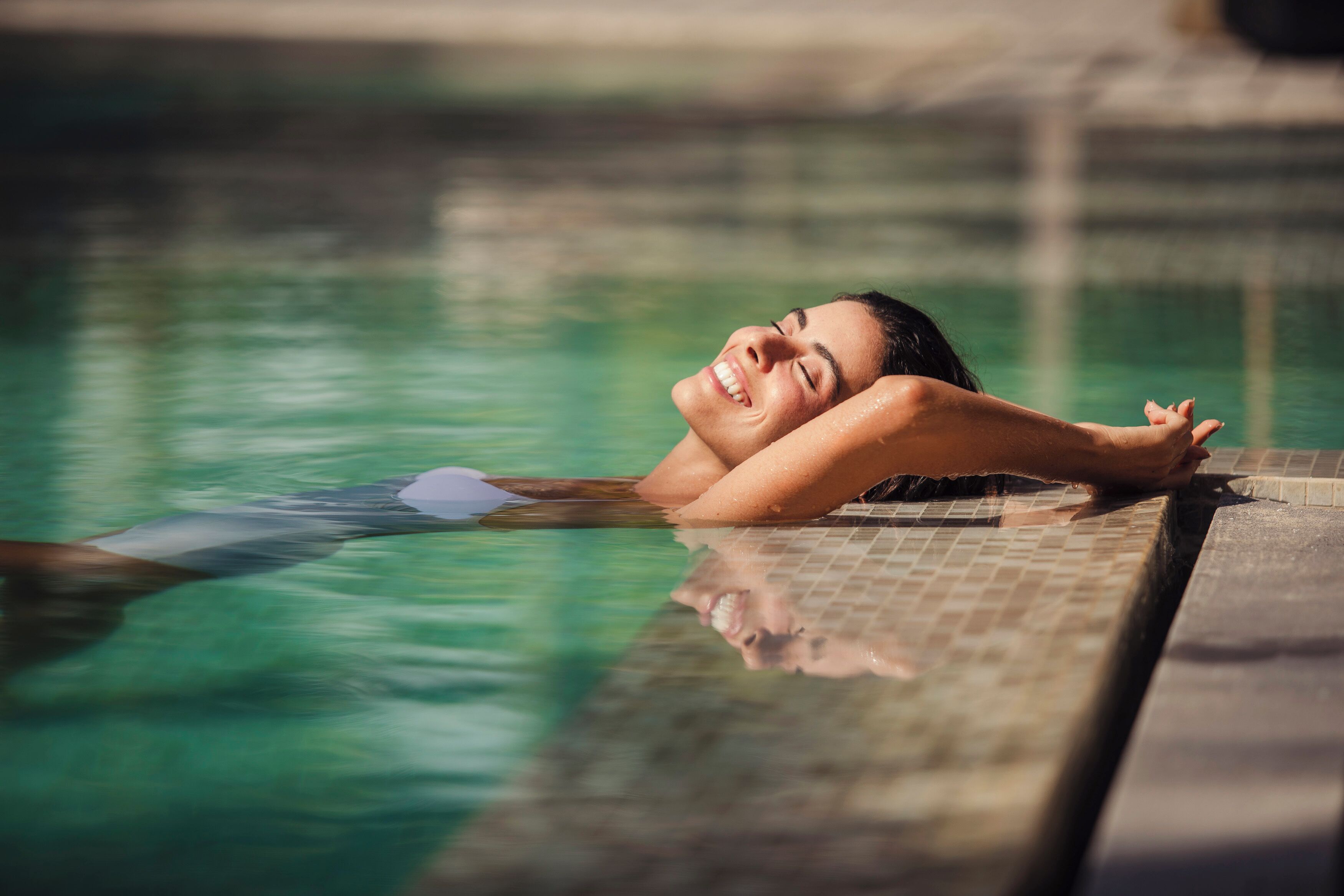 A person relaxing in a swimming pool with clear water.